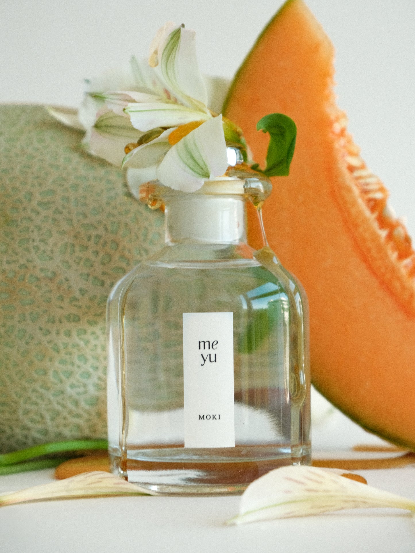 Moki reed diffuser displayed with melon and magnolia flowers - sweet fruity home fragrance by Meyu Vancouver