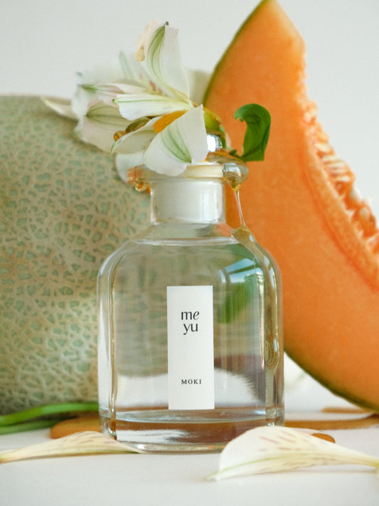 Moki reed diffuser displayed with melon and magnolia flowers - sweet fruity home fragrance by Meyu Vancouver
