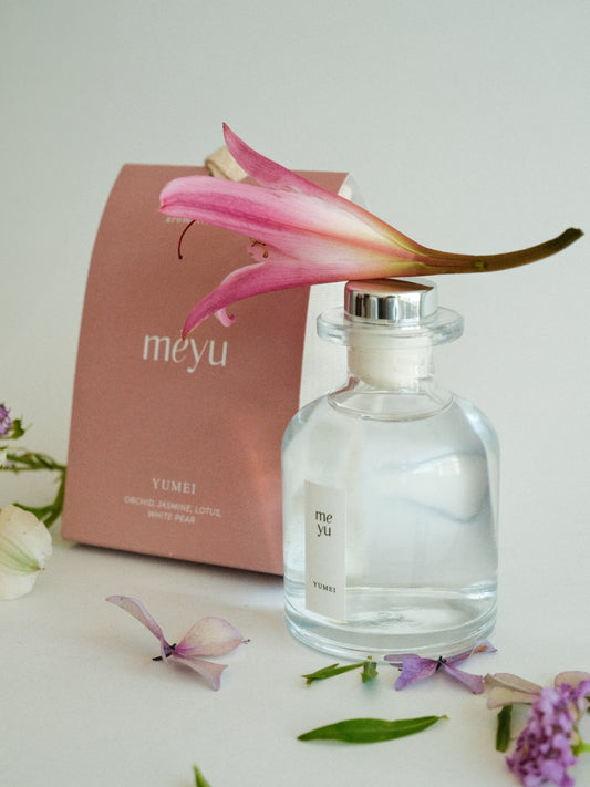 Yumei gift set with reed diffuser and scented sachet on white background with flower petal accents - floral home fragrance by Meyu Vancouver